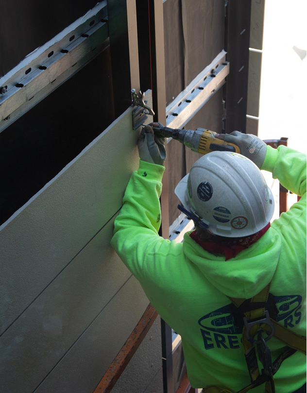 Installation of UHPC façade panel showing mounting bracket and support system.